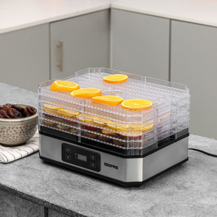 Countertop food dehydrator with multiple transparent trays holding sliced oranges